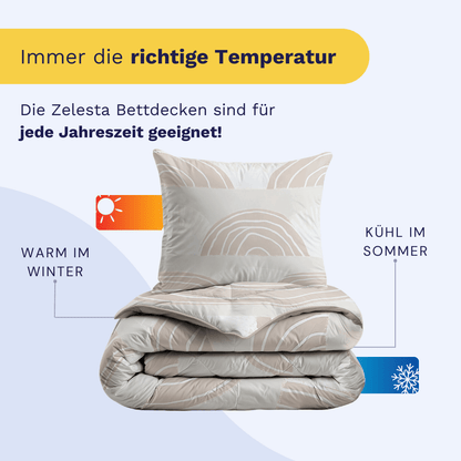 Eine gefaltete Bettdecke mit einem Kopfkissen obenauf; Symbole und Text heben hervor, dass das Zelesta Kiddybed Baumwolle - Dune Dreams hypoallergen ist, im Winter warm und im Sommer kühl hält und für alle Jahreszeiten geeignet ist.