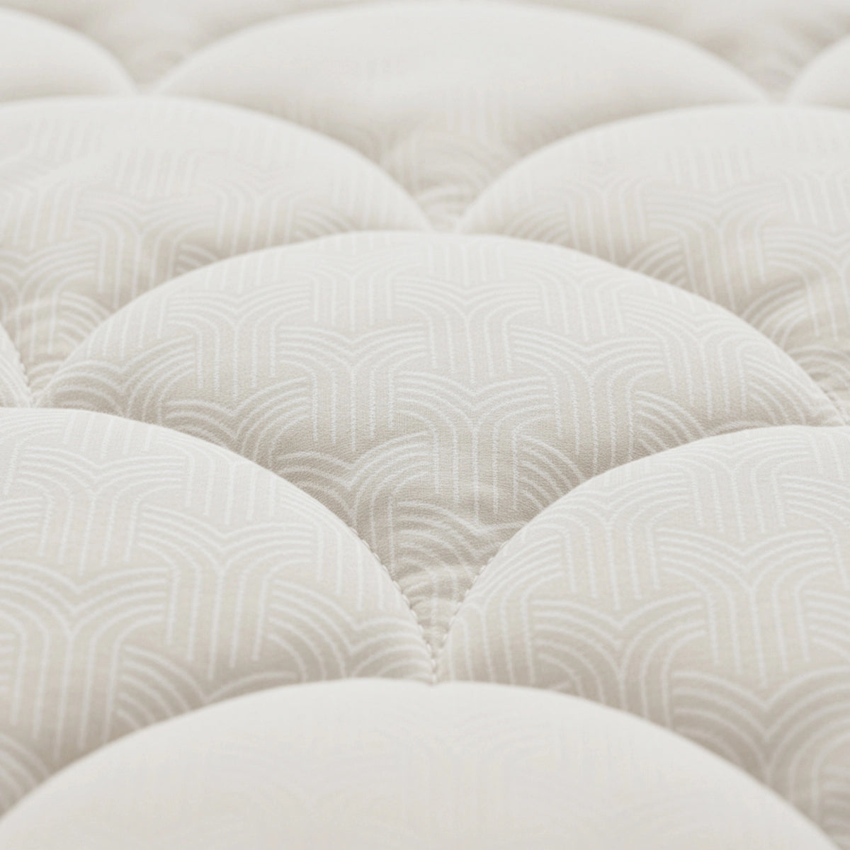 Nahaufnahme der Zelesta Flanel Luxe - Creme: eine weiße, gesteppte Matratzenoberfläche mit dezentem geometrischem Muster und geschwungenen, gepolsterten Partien - ideal zur Kombination mit dieser temperaturregulierenden Bettdecke für optimalen Schlafkomfort.