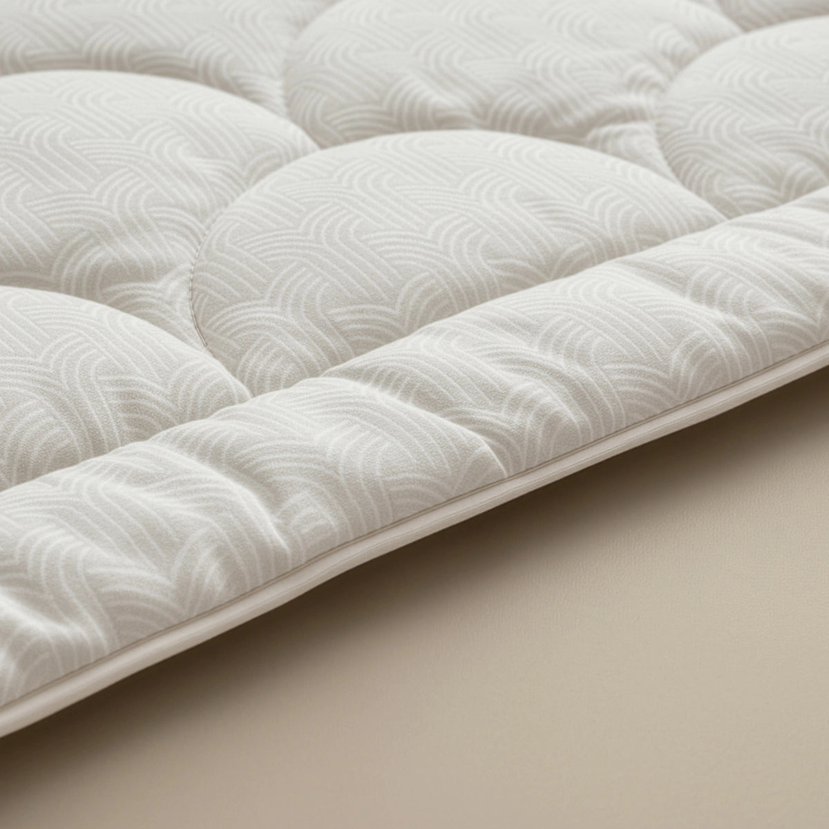 Nahaufnahme der Zelesta Flanel Luxe - Creme gesteppten Matratzenauflage mit dezentem geometrischem Muster, ideal für die Verwendung mit einer temperaturregulierenden Bettdecke zur Steigerung des Komforts.