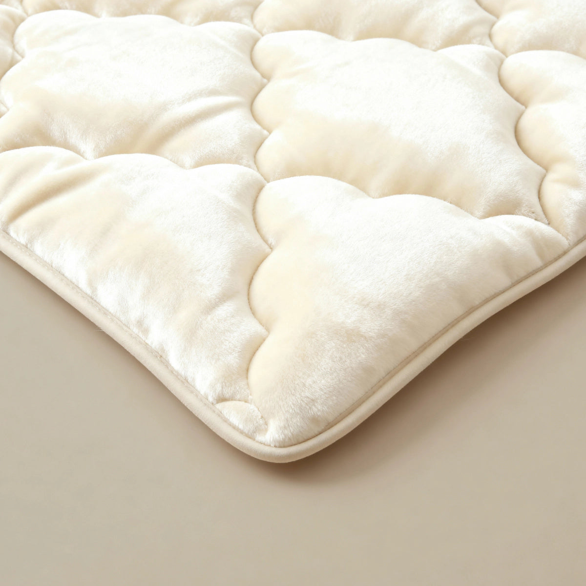 Nahaufnahme der Zelesta Flanel Uni - Beige, einer cremefarbenen, gesteppten Plüschmatratzenauflage mit weicher, samtiger Textur - ideal für zusätzlichen Komfort und perfekt, um sie das ganze Jahr über mit einer temperaturregulierenden Bettdecke zu kombinieren.