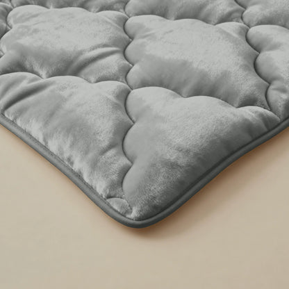 Nahaufnahme der Zelesta Flanel Uni - Khaki Matratzenauflage mit einer grauen, gesteppten, samtigen Oberfläche und wolkenartigem Muster auf beige-perfekt für extra Weichheit und temperaturregulierenden Komfort.
