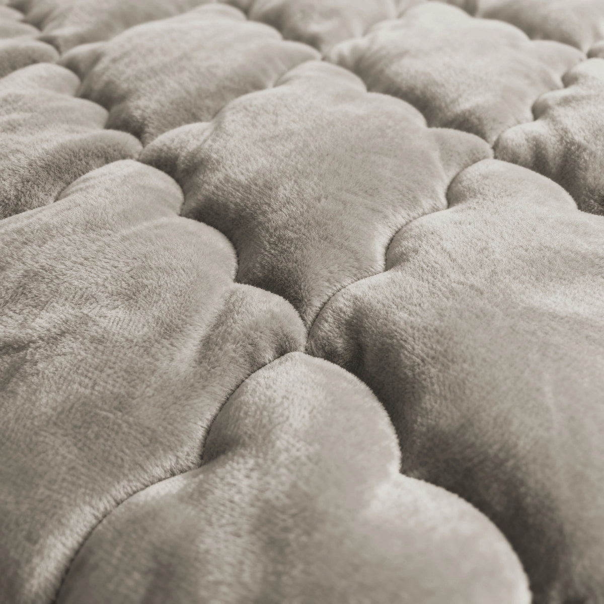 Nahaufnahme der weichen, gesteppten Oberfläche von Zelesta Flanel Uni - Taupe, mit wolkenförmigen, gepolsterten Abschnitten in einem hellen Taupe-Ton.