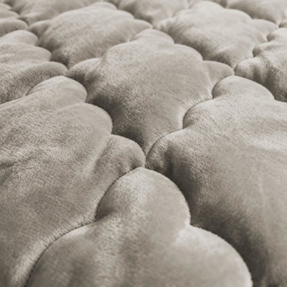 Nahaufnahme der weichen, gesteppten Oberfläche von Zelesta Flanel Uni - Taupe, mit wolkenförmigen, gepolsterten Abschnitten in einem hellen Taupe-Ton.