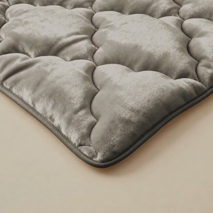 Nahaufnahme der Zelesta Flanel Uni - Taupe Bettdecke mit einer gesteppten, samtig weichen taupefarbenen Mikrofasertextur mit abgerundeten Nähten auf hellem Hintergrund.