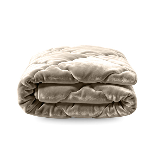 Die Zelesta Flanel Uni - Taupe ist eine gefaltete Mikrofaser-Bettdecke aus weichem, plüschigem Stoff in hellem Beige, die auf weißem Hintergrund für behagliche Nächte sorgt.