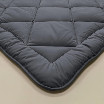 Nahaufnahme einer dunkelgrauen, gesteppten Zelesta Royalbed Diamant - Anthrazit Bettdecke mit gepolstertem, allergenfreundlichem Material und sichtbaren Nähten, dargestellt auf einer beigen Oberfläche.