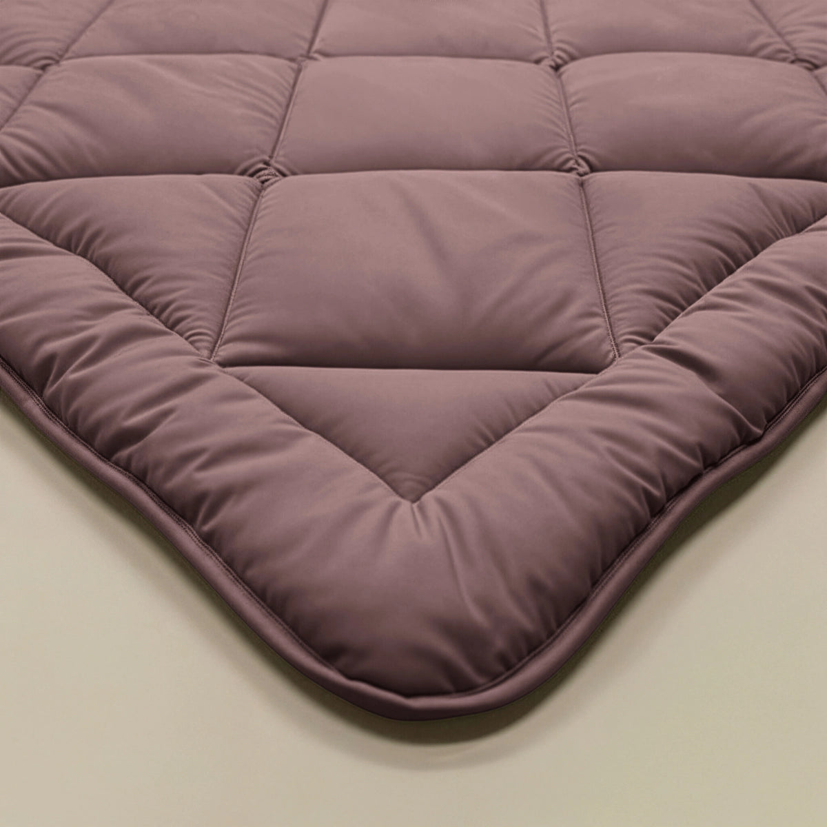 Eine Nahaufnahme der Zelesta Royalbed Diamant - Bordeaux, einer malvenfarbenen Decke mit temperaturregulierender, allergikerfreundlicher Füllung und einem strukturierten Steppmuster.