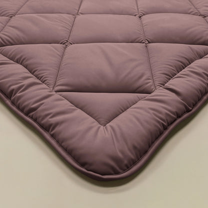 Eine Nahaufnahme der Zelesta Royalbed Diamant - Bordeaux, einer malvenfarbenen Decke mit temperaturregulierender, allergikerfreundlicher Füllung und einem strukturierten Steppmuster.