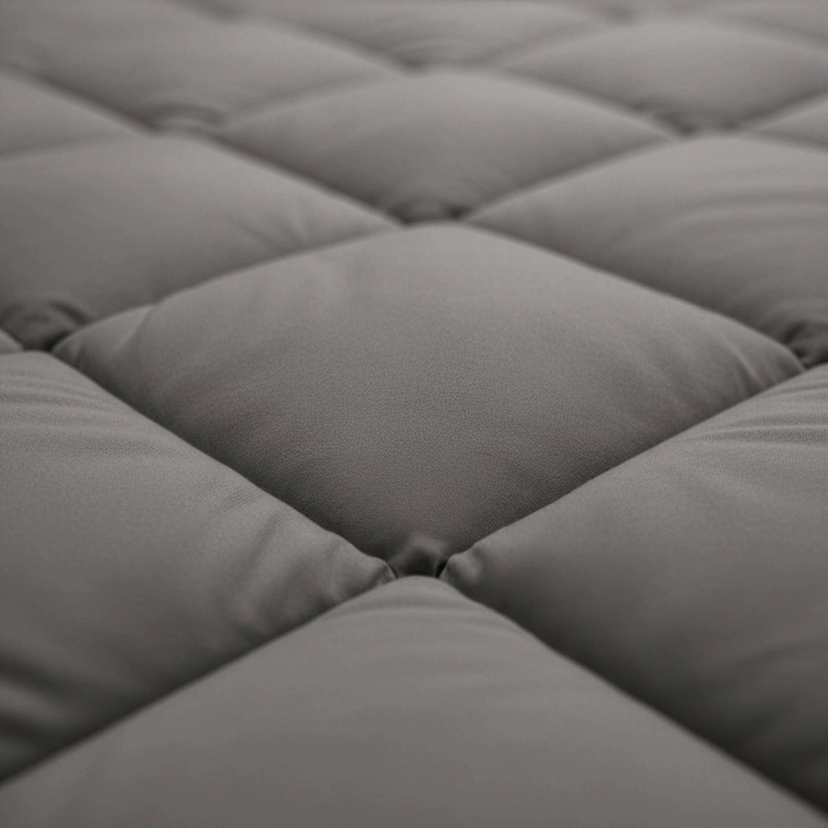 Nahaufnahme der gesteppten Oberfläche des Zelesta Royalbed Diamant - Brown-Grey, mit weichen Mikrofaserquadraten in einem Rautenmuster.