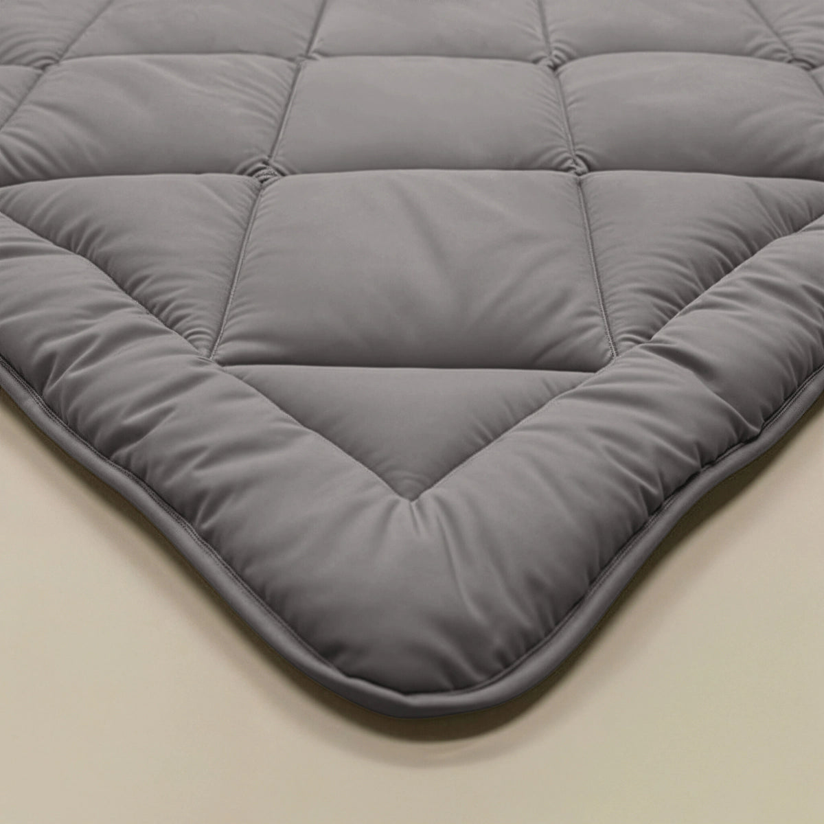 Nahaufnahme einer braun-grauen Steppdecke, der Zelesta Royalbed Diamant, mit abgesteppten quadratischen Mustern auf einer hellen Oberfläche.