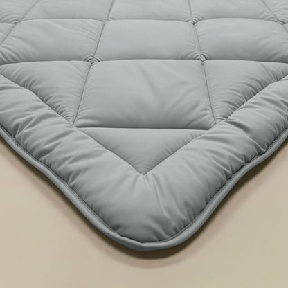 Nahaufnahme einer grau-blauen, gesteppten Zelesta Royalbed Diamant - Grey-Blue Bettdecke mit quadratischen Nähten, die flach auf einer beigefarbenen, allergikergeeigneten Bettdecke liegt, die ideal für Komfort und Unterstützung ist.