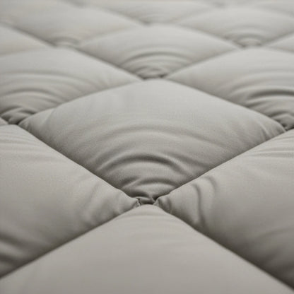 Nahaufnahme eines hellgrauen, gesteppten Stoffes mit gleichmäßig gepolsterten Quadraten und sichtbaren Nähten, die das temperaturregulierende Zelesta Royalbed Diamant - Sand-Beige zeigen, ideal als allergikergeeignete Bettdecke.