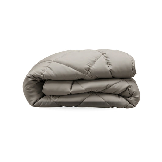Eine gefaltete, sand-beige Zelesta Royalbed Diamant Bettdecke ist gesteppt und auf einem weißen Untergrund platziert - eine edle, temperaturregulierende Bettdecke für höchsten Schlafkomfort.