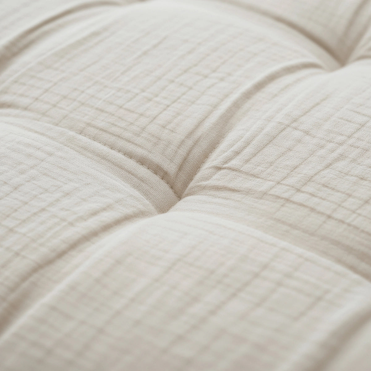Nahaufnahme von Zelesta Teddy Baumwolle Musselin - Beige, mit gestepptem cremefarbenem Stoff mit sichtbaren Nähten und weicher, temperaturregulierender Tufting-Polsterung.
