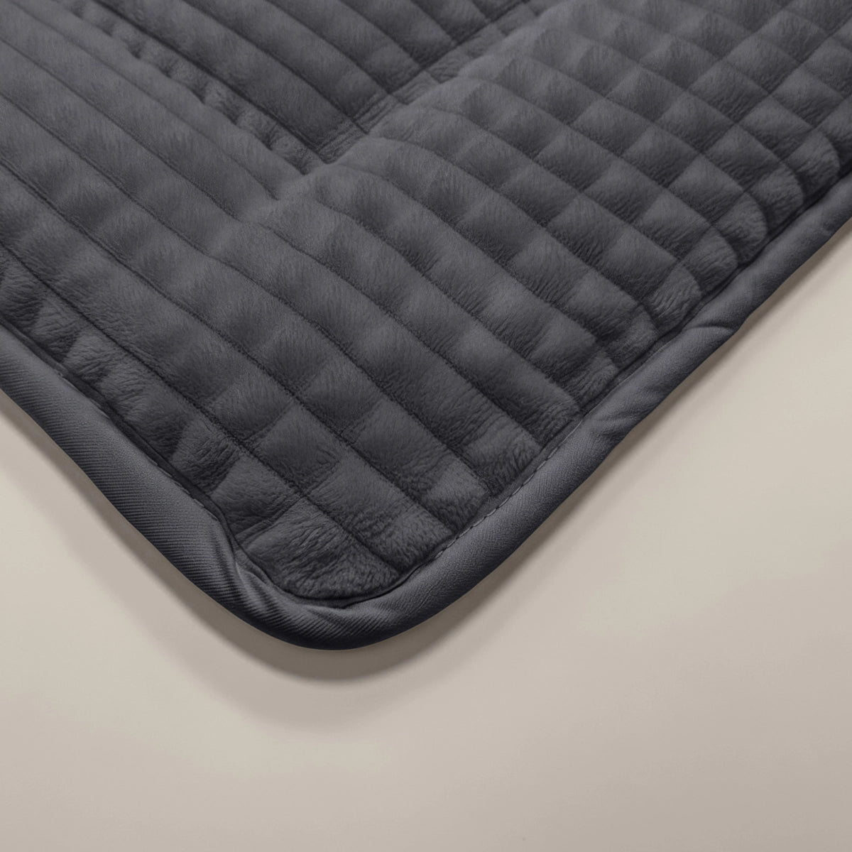 Nahaufnahme der Zelesta Teddy Check - Anthrazit Steppmatte mit abgerundeten Ecken, dargestellt auf einer hellen Fläche.