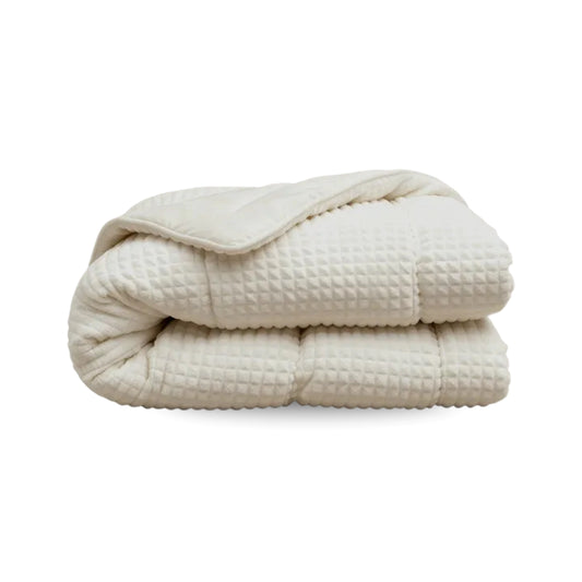 Die Zelesta Teddy Check - Créme, eine cremefarbene Mikrofaserdecke mit Waffelmuster, ist gefaltet auf weißem Hintergrund abgebildet.