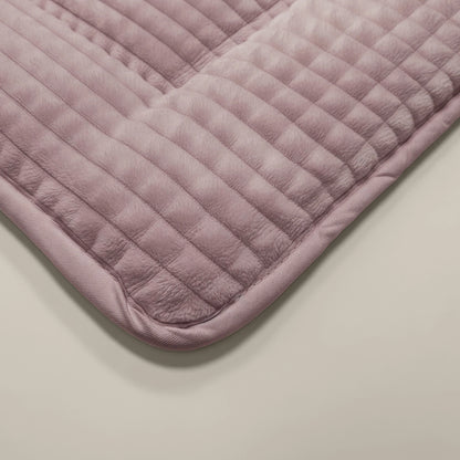 Eine Nahaufnahme der Zelesta Teddy Check - Old Pink Matte mit einem gesteppten, rosafarbenen Design mit abgerundeten Kanten auf einer hellen Oberfläche, die die gemütliche, von einer Mikrofaser Bettdecke inspirierte Textur zeigt.