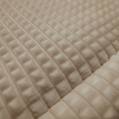Die Nahaufnahme von Zelesta Teddy Check - Taupe zeigt einen strukturierten beigen Stoff mit einem gesteppten, rechteckigen Muster und erhöhten, gepolsterten Abschnitten, die an eine Mikrofaser-Bettdecke erinnern.