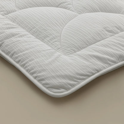 Nahaufnahme der Zelesta Flanel Velvetbed Chique Matratzenauflage in Beige mit einer strukturierten, temperaturregulierenden Füllung und abgerundeten Ecken auf einer leichten Oberfläche - perfekt für ein luxuriöses Schlafzimmer.