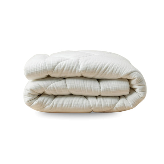 Das Zelesta Flanel Velvetbed Chique in Beige ist eine gefaltete, gesteppte Bettdecke mit temperaturausgleichender Füllung auf einem schlichten weißen Untergrund - ideal für ein luxuriöses Schlafzimmer.