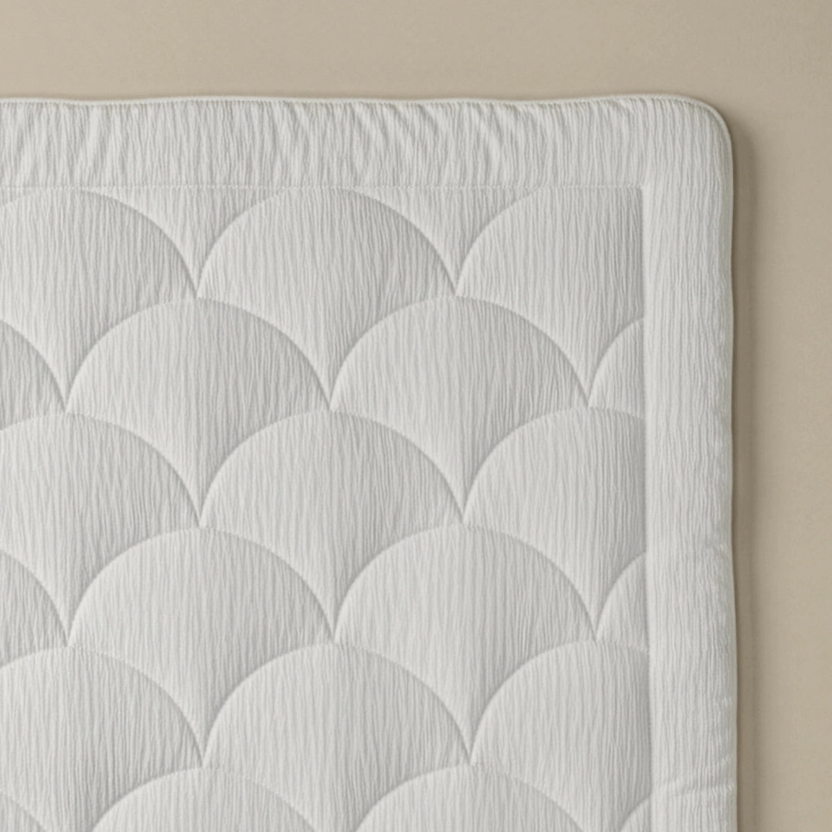 Nahaufnahme des gesteppten weißen Stoffs mit fächerförmiger Steppung auf neutralem Hintergrund, ideal für das Zelesta Flanel Velvetbed Chique - Beige, das Ihrem Schlafzimmer Luxus verleiht.