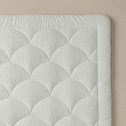 Nahaufnahme des gesteppten weißen Stoffs mit fächerförmiger Steppung auf neutralem Hintergrund, ideal für das Zelesta Flanel Velvetbed Chique - Beige, das Ihrem Schlafzimmer Luxus verleiht.