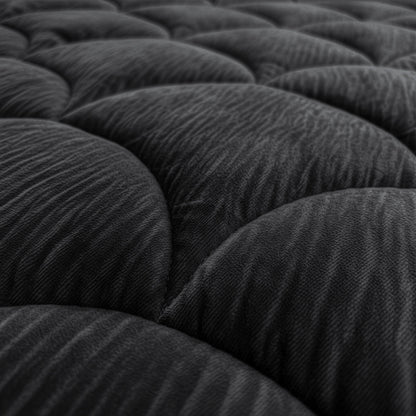 Die Nahaufnahme der dunklen, strukturierten, gesteppten Oberfläche mit geschwungenen, gepolsterten Abschnitten unterstreicht das elegante Design des Zelesta Flanel Velvetbed Chique - Black, ideal für ein luxuriöses Schlafzimmer.