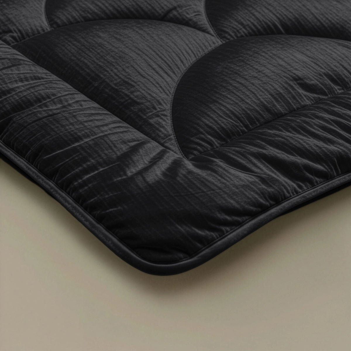 Nahaufnahme des Zelesta Flanel Velvetbed Chique - Black, einer schwarzen Steppdecke mit strukturierter Oberfläche, auf hellem Hintergrund - ideal, um Ihrem Schlafzimmer Luxus zu verleihen.